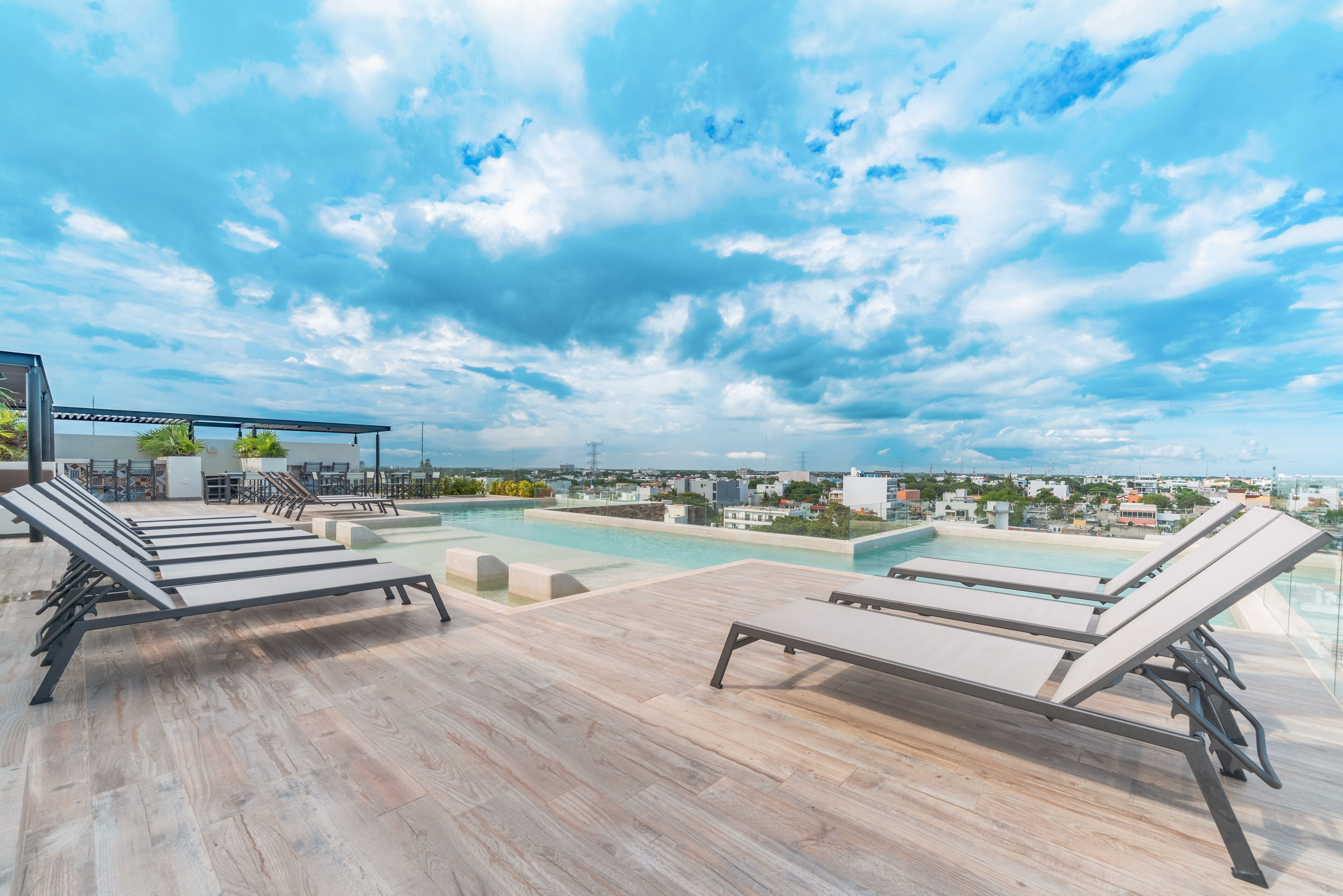 Un espace piscine aménagé sur le toit, avec des chaises longues et une vue sur le paysage urbain.