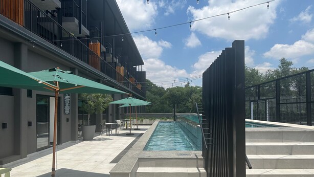 Un espace piscine extérieur moderne, offrant une vue dégagée sur le ciel, avec une piscine à plusieurs niveaux et des espaces de détente en plein air agrémentés de parasols.