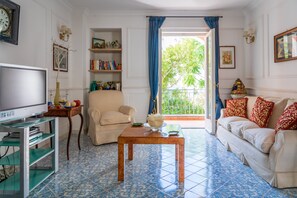 Una sala de estar con televisor, sofá, sillón, mesa de centro y estantería.