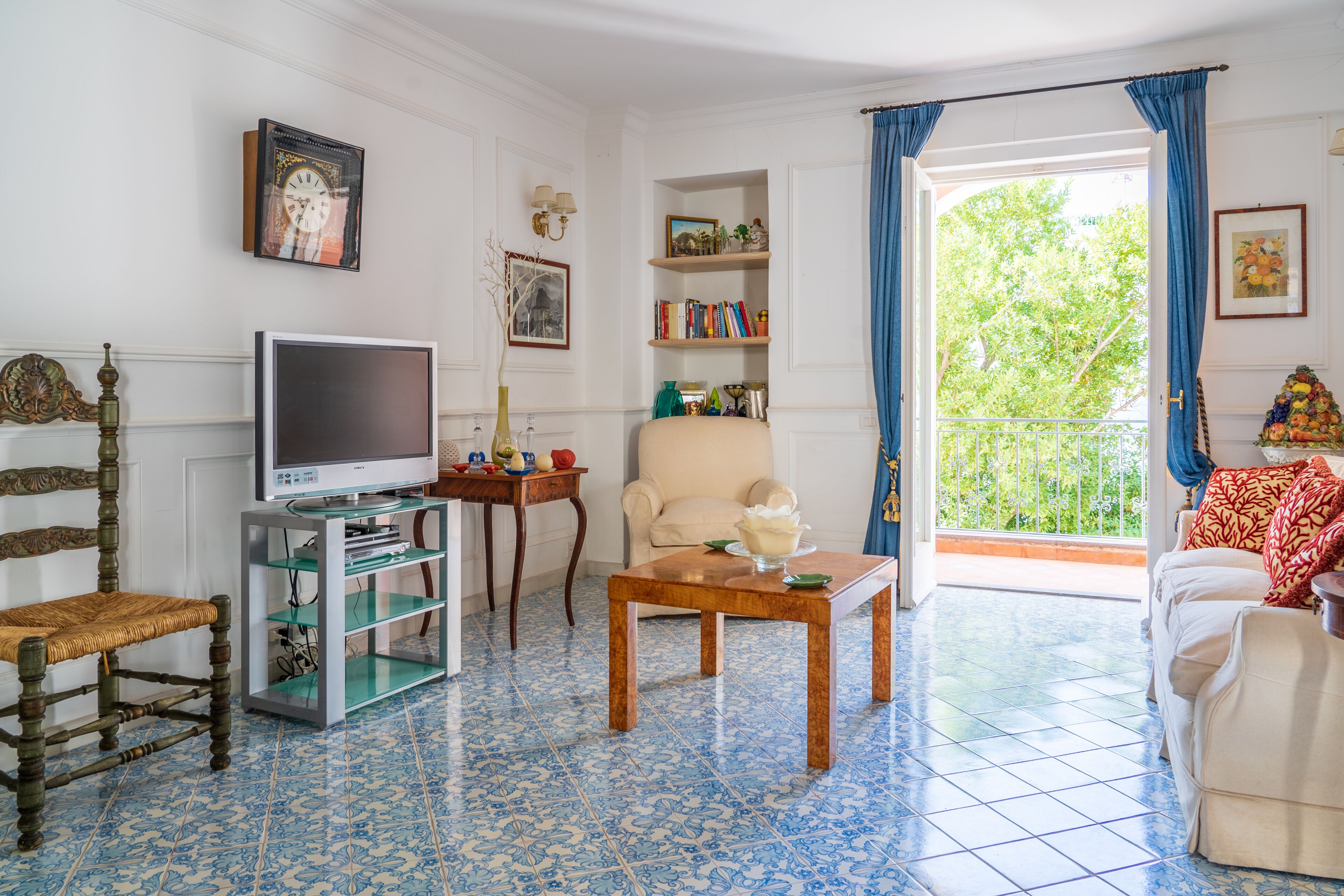 A living room with a television, a chair, a table, and a bookshelf.