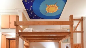 A bunk bed with a wooden frame, a plaid bedspread, and a ceiling mural of stars and a sun. - Accogliente Appartamento (Roma)