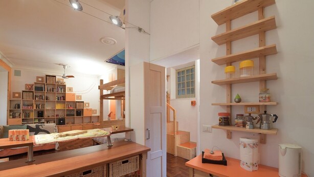 A cozy room with a wooden table, a bookshelf, a bunk bed, and a staircase leading to another room. - Accogliente Appartamento (Roma)