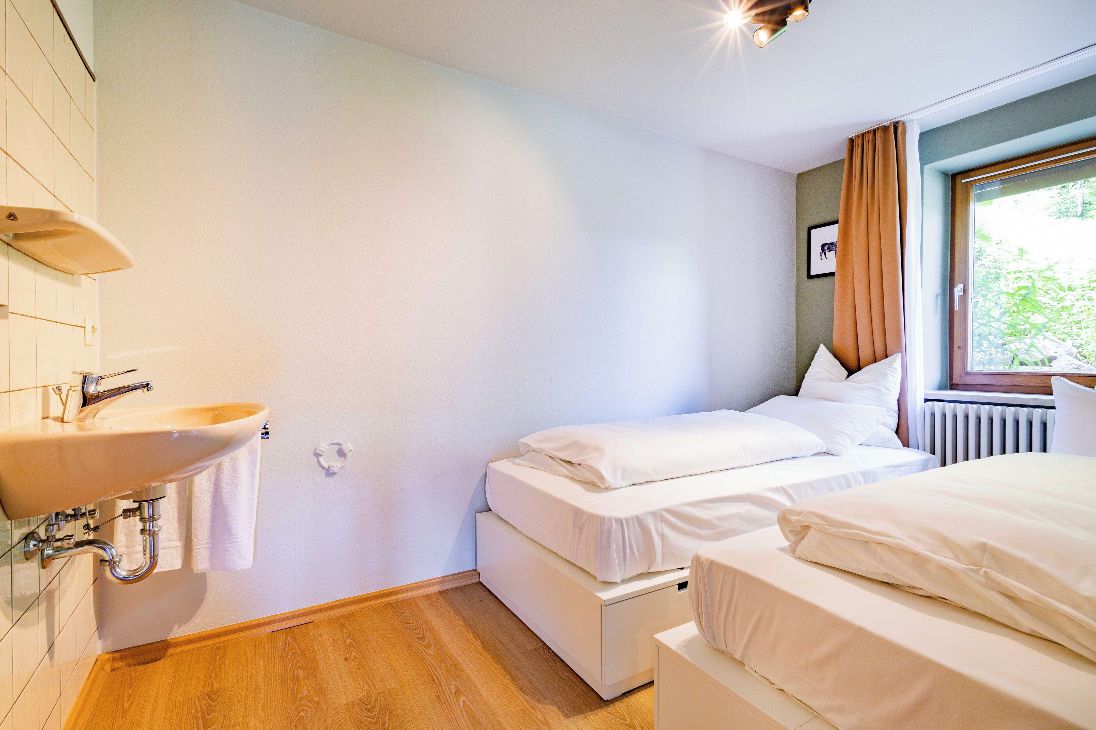 Una habitación de hotel con baño, una cama y un ventanal con cortinas.