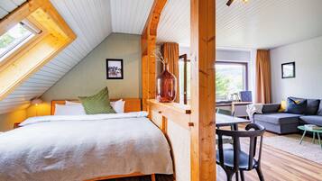 A cozy bedroom with a large bed, a wooden headboard, a window, and a view of the outdoors.