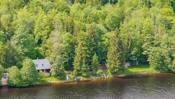 A house surrounded by dense forest and a body of water.