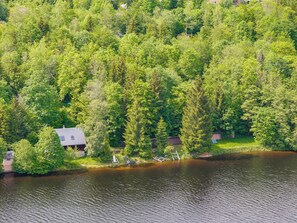 Una casa circondata da una fitta foresta e da uno specchio d'acqua.
