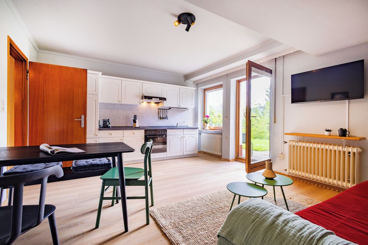A modern kitchen with white cabinets, a built-in oven, and a large window.