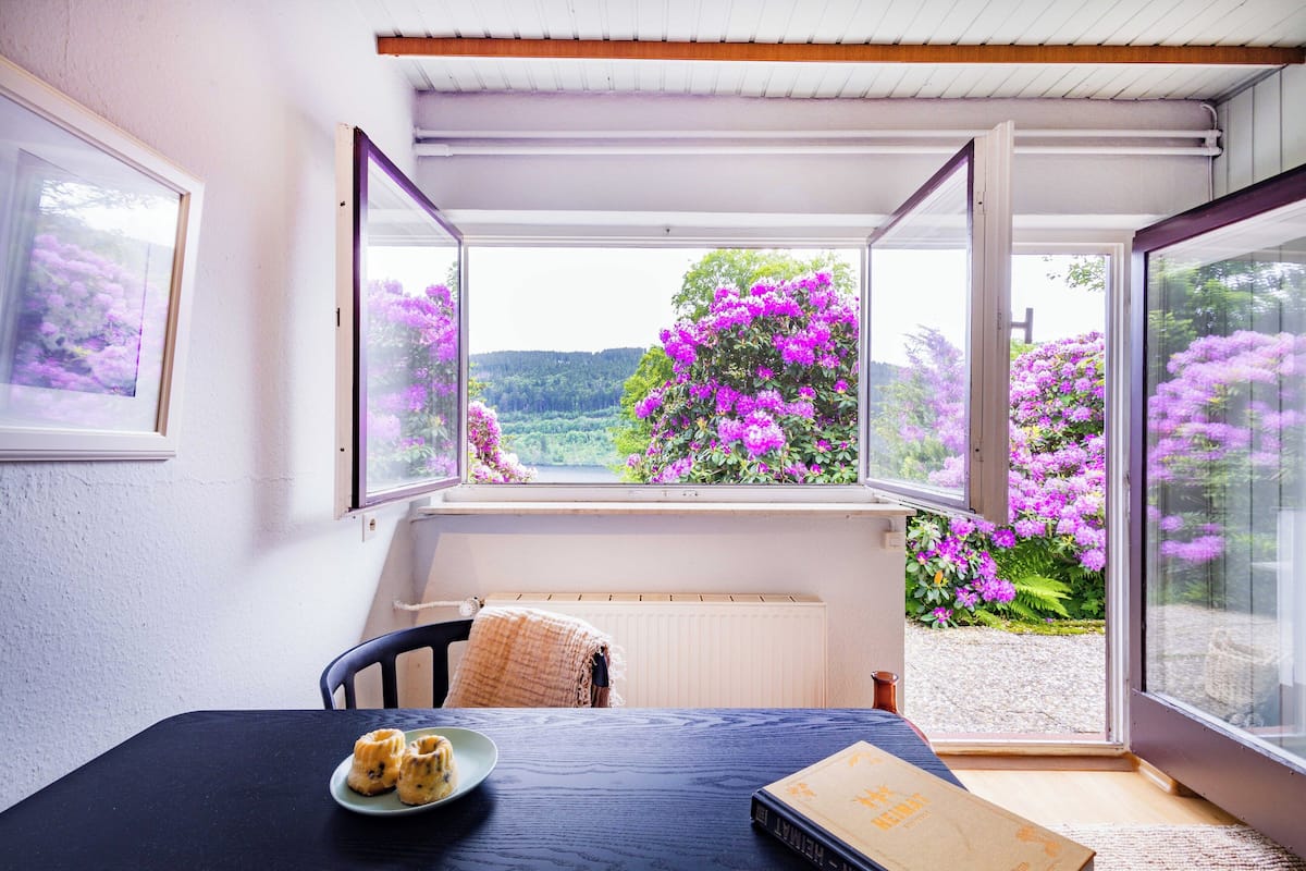 A room with a table, a chair, and a window with an open door.