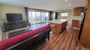 Una cocina moderna con armarios de madera, una isla central y un amplio ventanal corredero que da a un balcón.