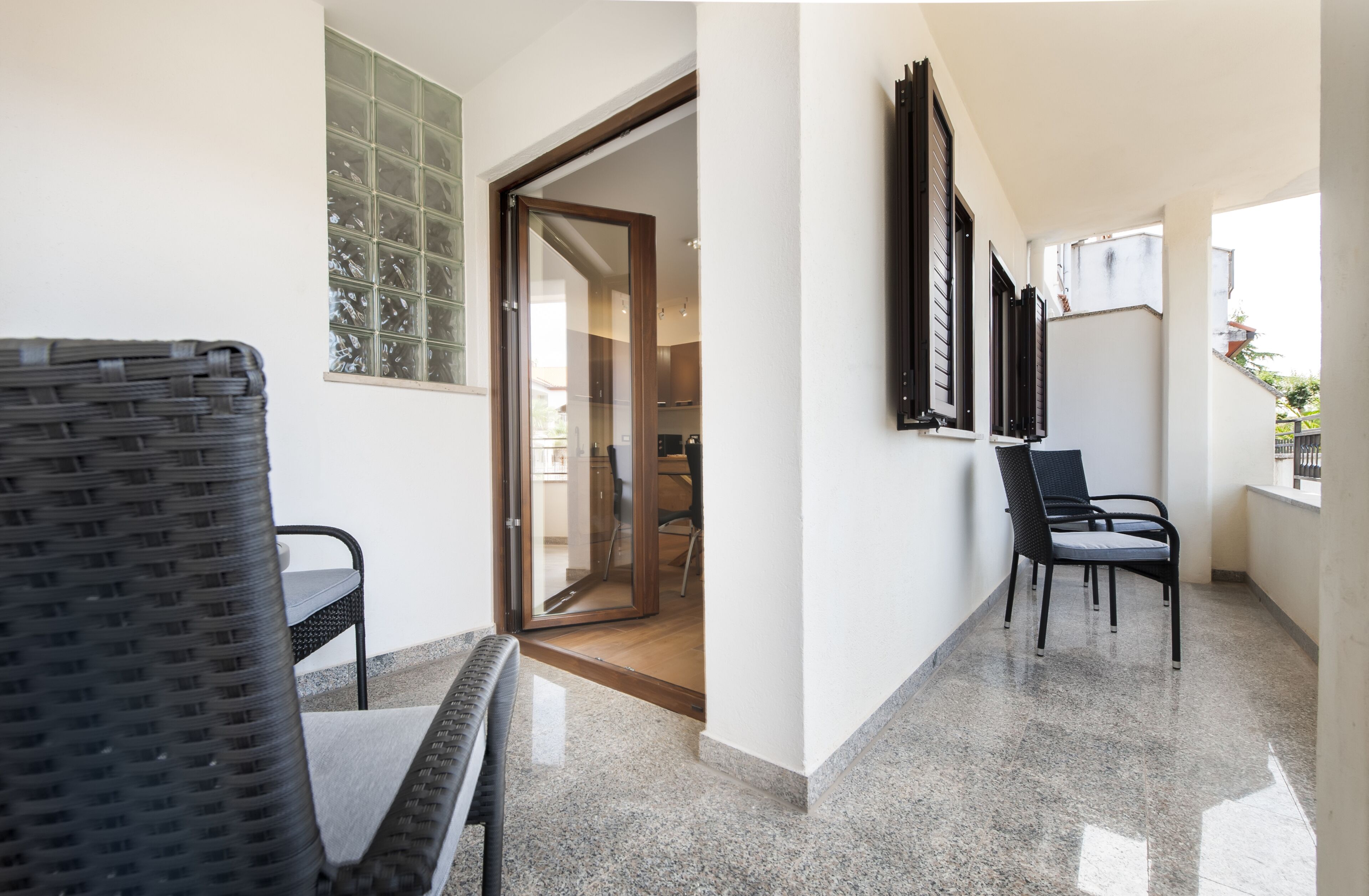 A hallway with a dining area, a glass door leading to a kitchen, and a view of the outside.