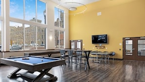 A pool table in a room with large windows, a flat-screen TV, and a yellow wall.