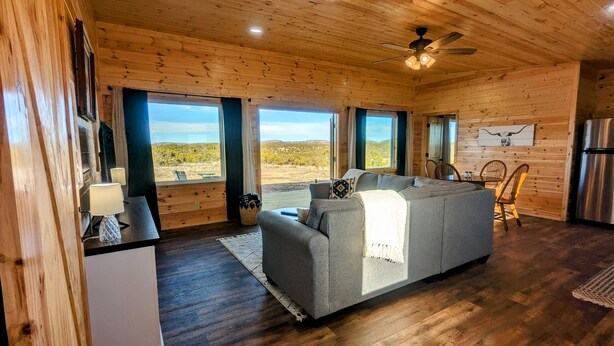 A log cabin with a sofa, dining table, chairs, and a refrigerator. - Peaceful quite cabin to kick back, relax and recharge! (Robert Lee)