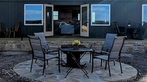 A modern building with a patio area featuring outdoor seating and a stone fire pit. - Peaceful quite cabin to kick back, relax and recharge! (Robert Lee)