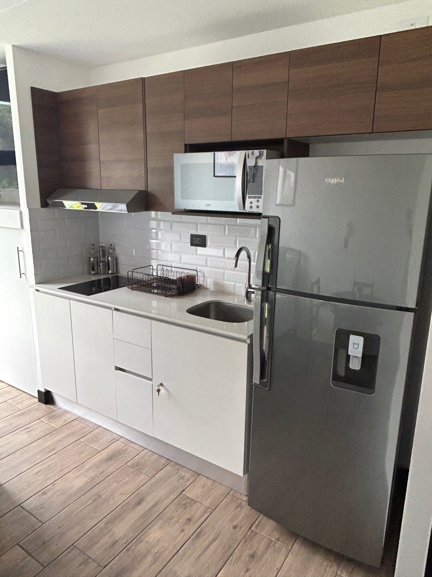 Een moderne keuken met een roestvrijstalen koelkast, een magnetron en een spoelbak.