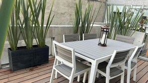 A wooden deck with a white table and chairs, surrounded by large green plants. - Amazing studio in Condesa (Ciudad de México)