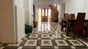 A hallway with a tiled floor, a staircase, and a dining area with chairs and a table. - Good Night (Tbilisi)