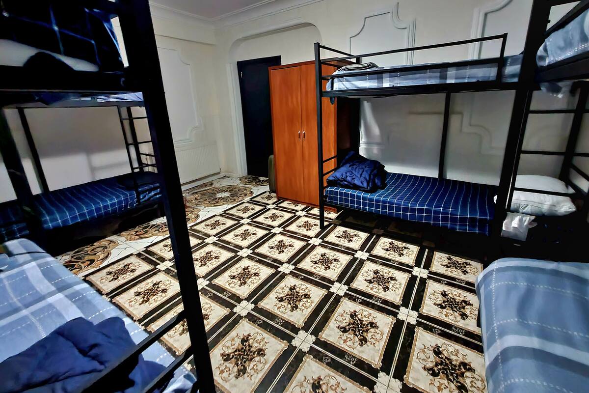 A room with bunk beds, a patterned floor, a wardrobe, and a door.