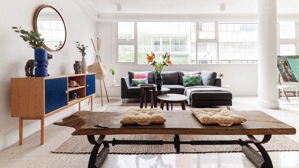 A modern living room with a wooden coffee table, a sofa, and a sideboard with decorative items.