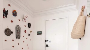 A hallway with a white door, a wall-mounted bag rack, and various decorative items.