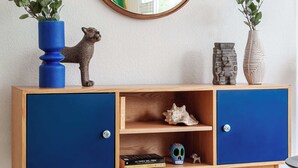 Un meuble en bois à deux portes, avec un miroir au-dessus, et deux vases avec des plantes de chaque côté.