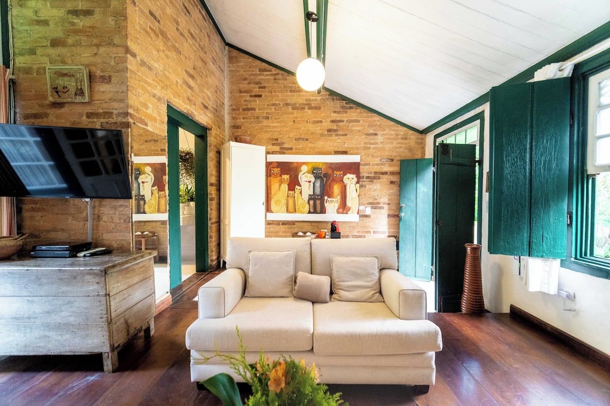 Un salon chaleureux avec un mur en briques, un canapé blanc et un meuble en bois.