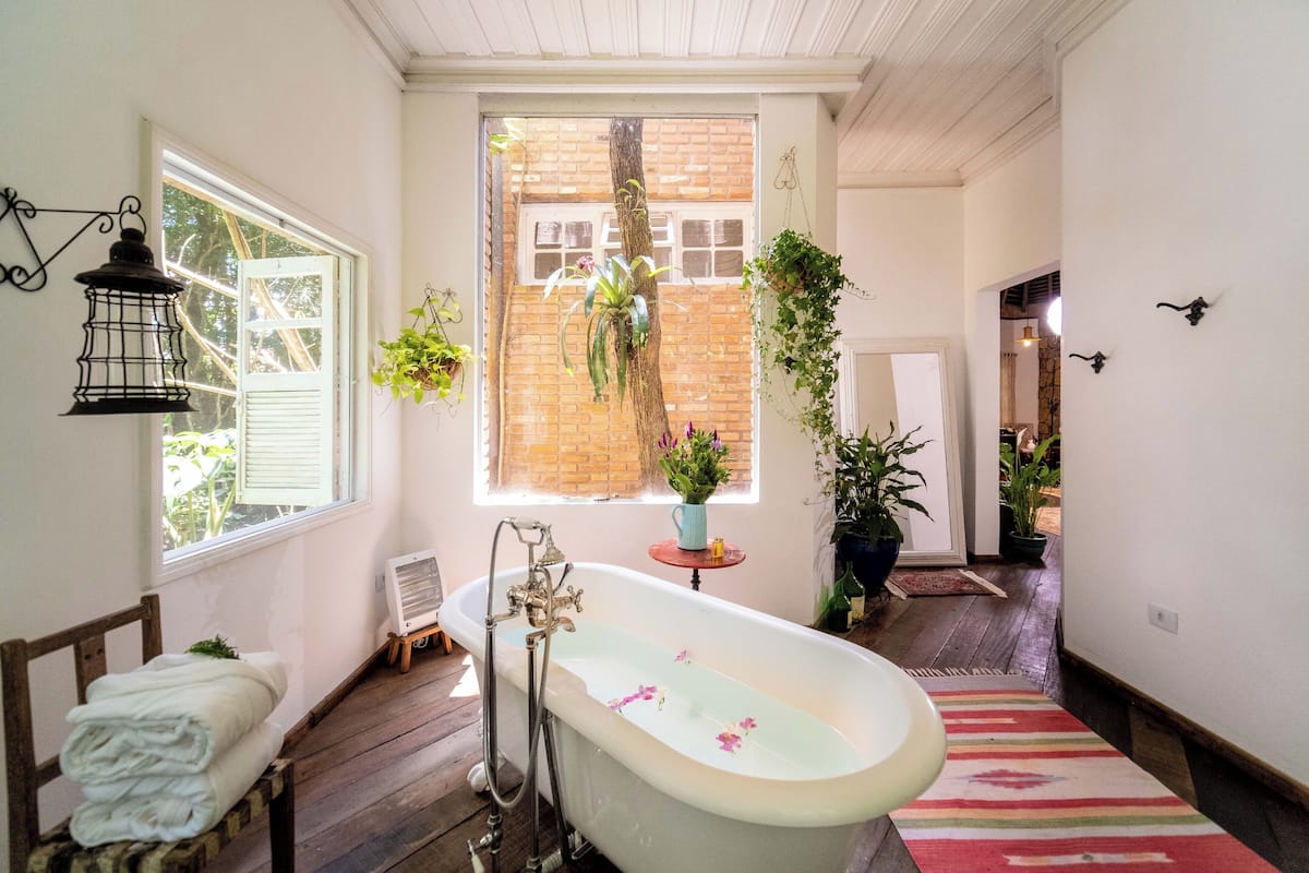 Une salle de bain avec une baignoire, une fenêtre et différentes plantes.