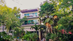 A modern building with multiple balconies and lush tropical vegetation. - Via 38 A13 - Modern Condo - At Via 38 (Playa del Carmen)