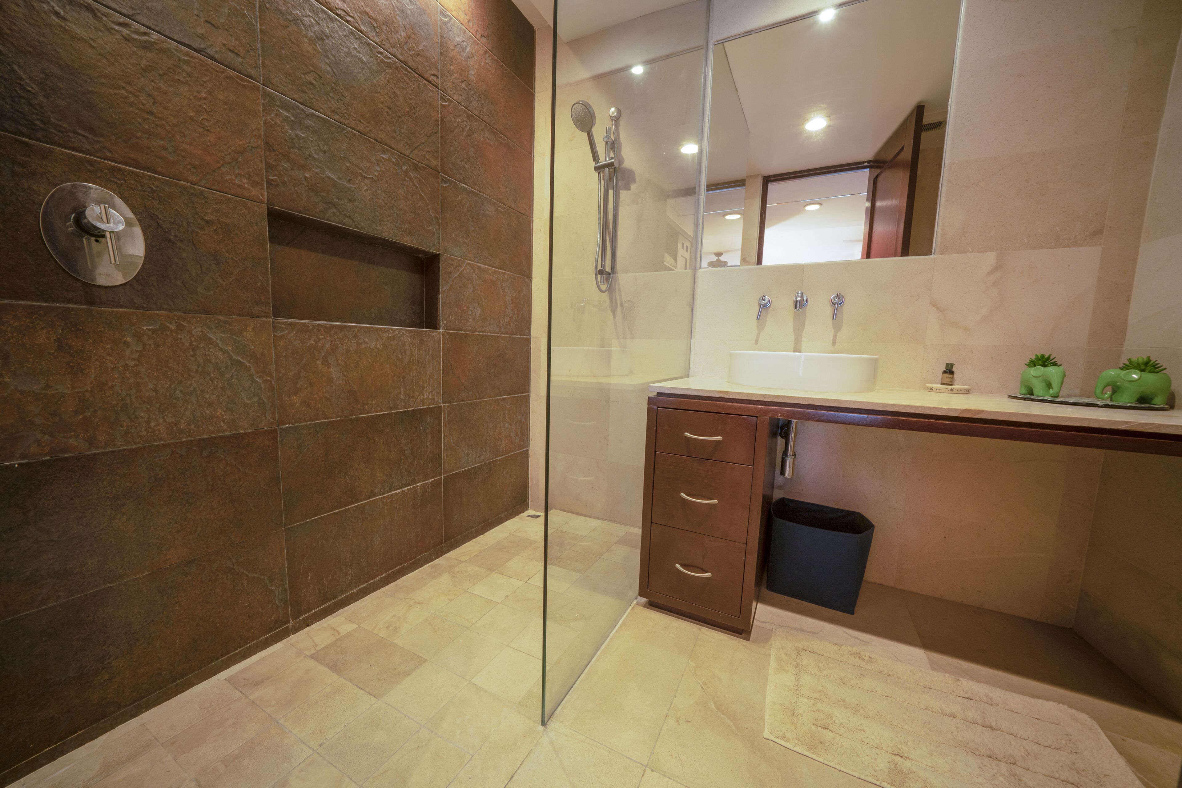 A modern bathroom with a glass shower enclosure, a marble-tiled wall, a wooden vanity with a sink, and a mirror above the vanity.