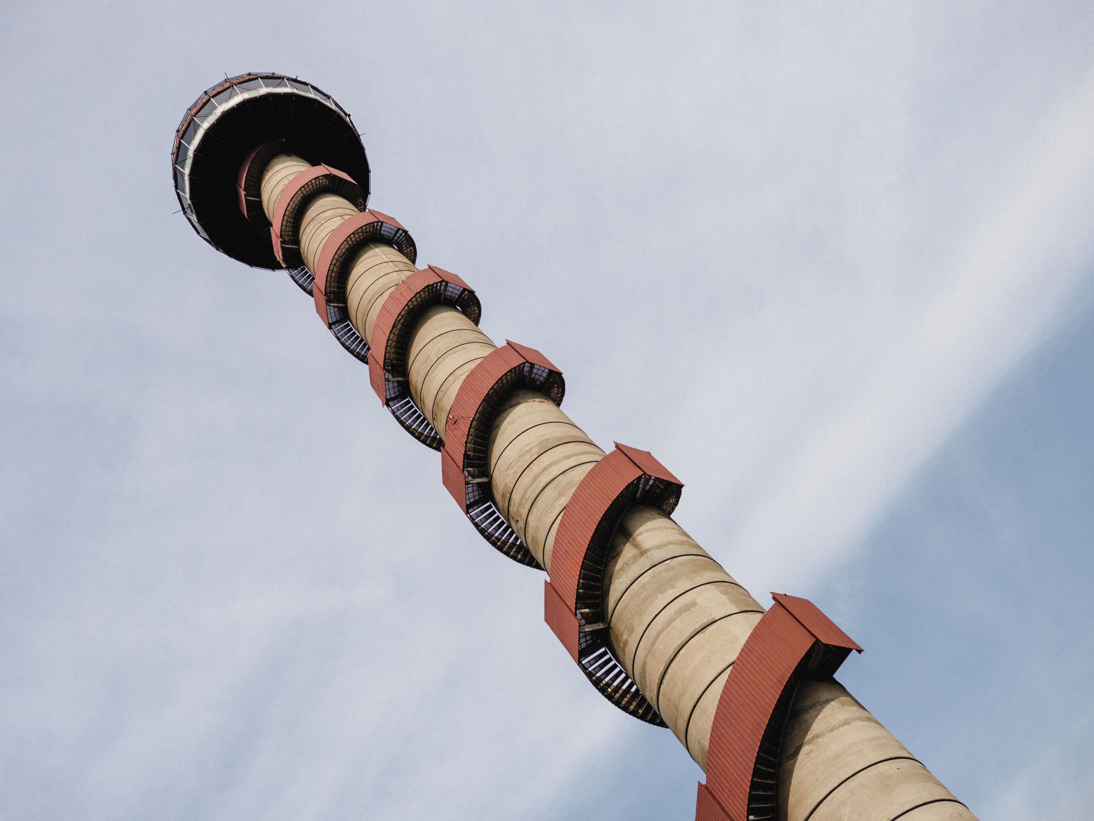 A tall, cylindrical structure with a series of rings and a circular top against a clear sky.