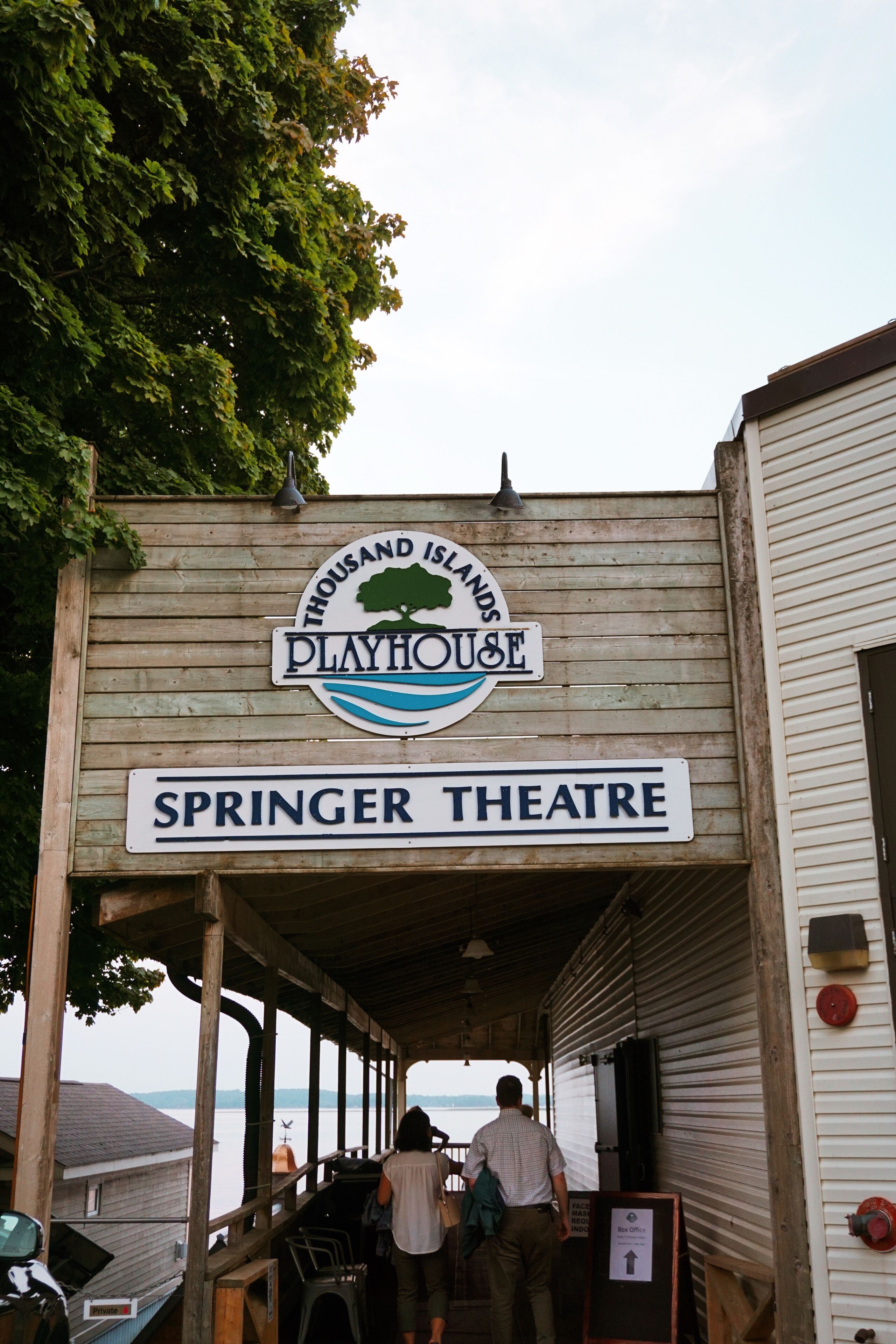 Ein Holzgebäude mit Schildern für 'Thousand Islands Playhouse' und 'Springer Theatre'.