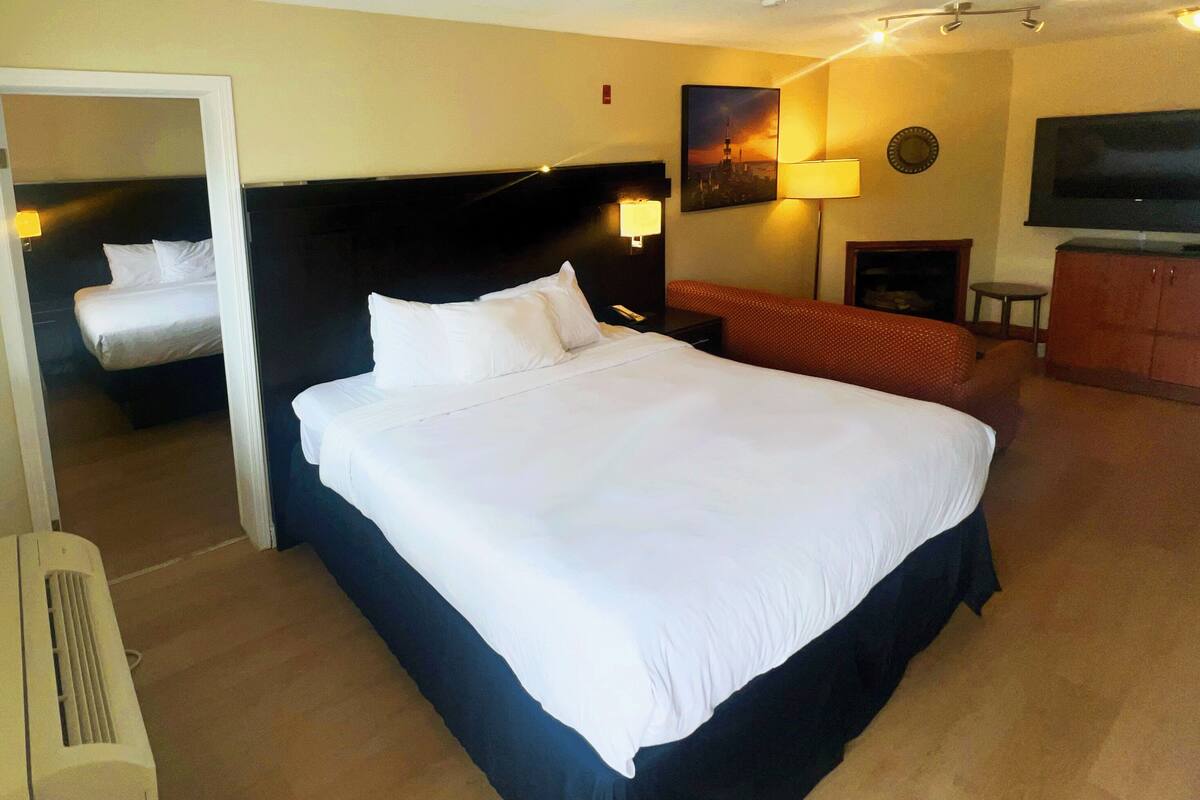 Ein Hotelzimmer mit einem großen Bett, einem Fernseher, einem Schreibtisch und einem Sessel.