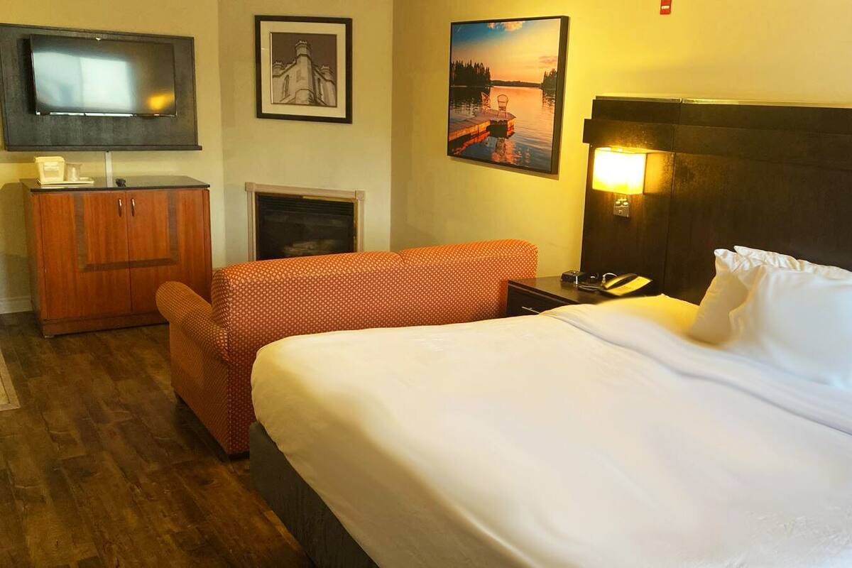 Ein Hotelzimmer mit Bett, Fernseher, Kamin und einem Gemälde an der Wand.