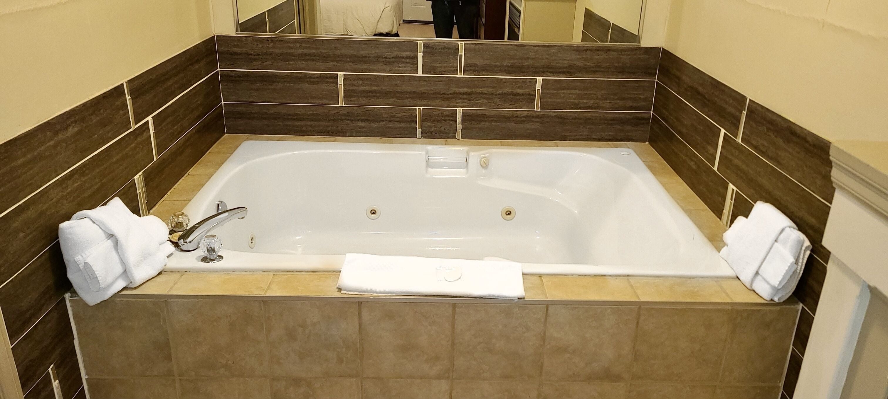 A rectangular bathtub with two towels, a glass, and a soap bar.