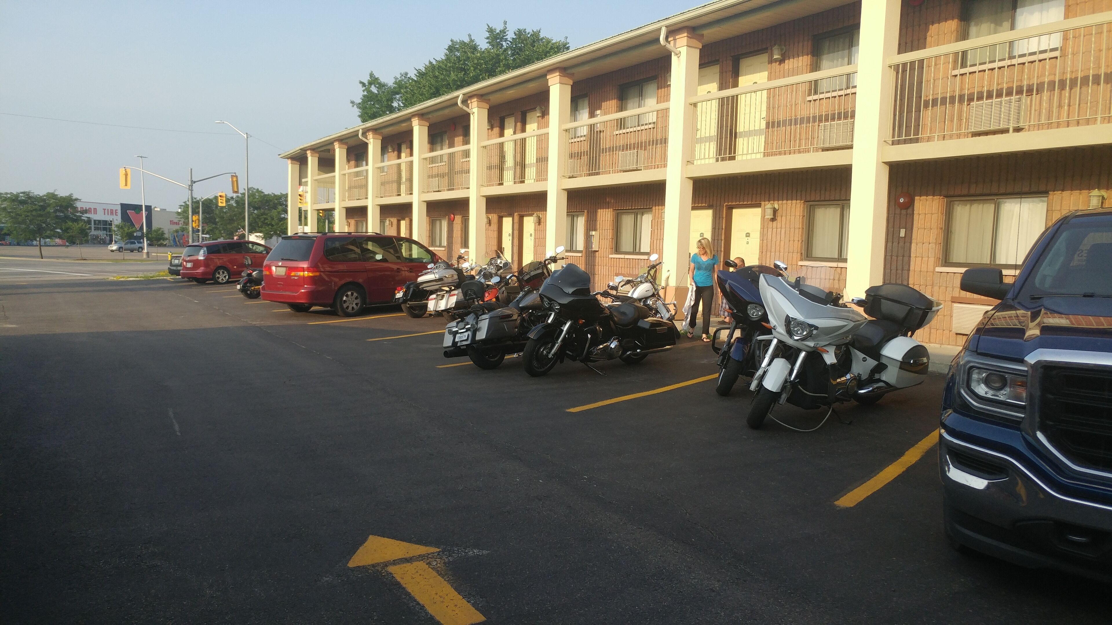 Um estacionamento com várias motocicletas e carros estacionados em frente a um edifício com varandas.