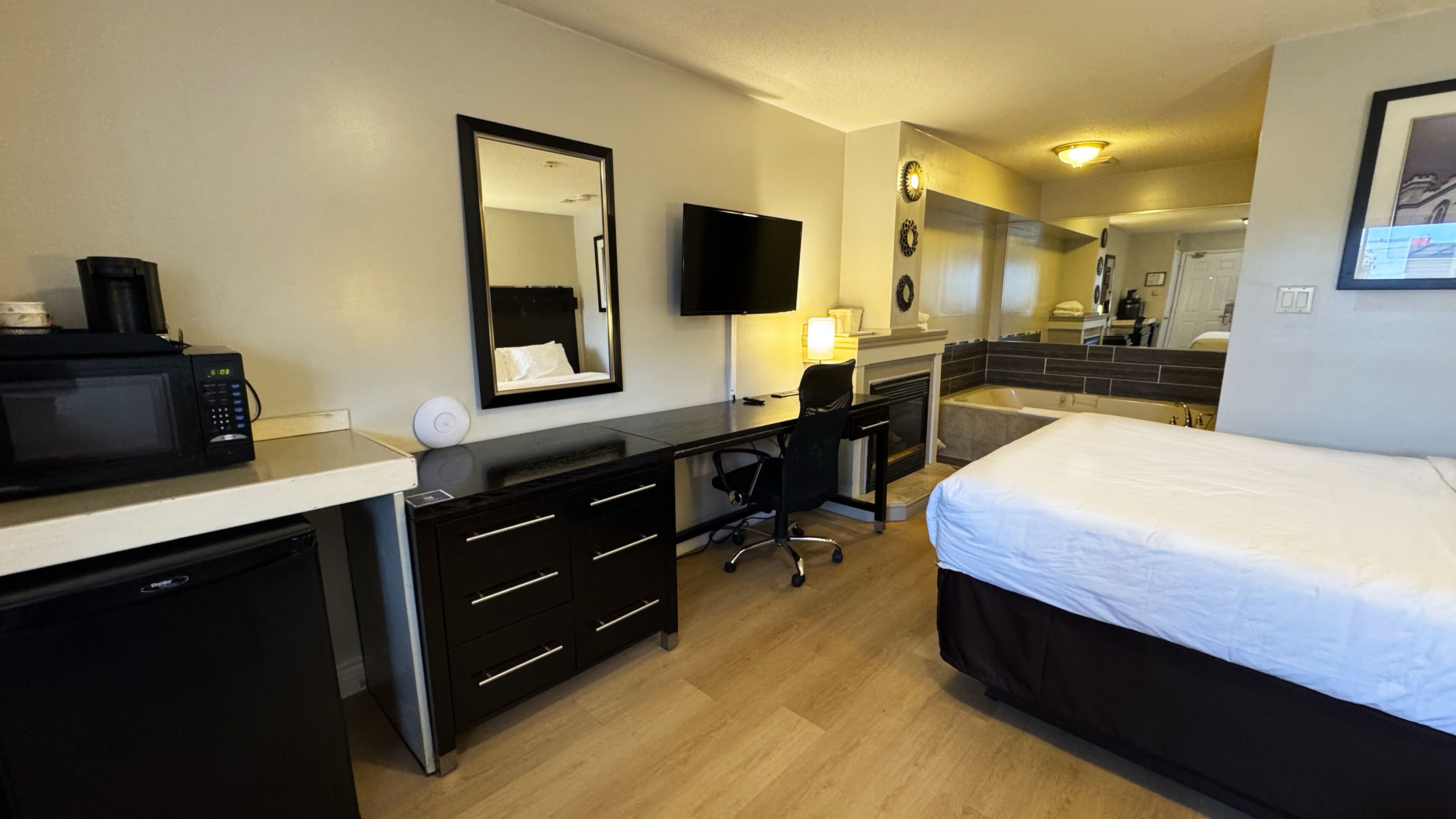 Habitación de hotel con cama, escritorio, microondas y televisión.