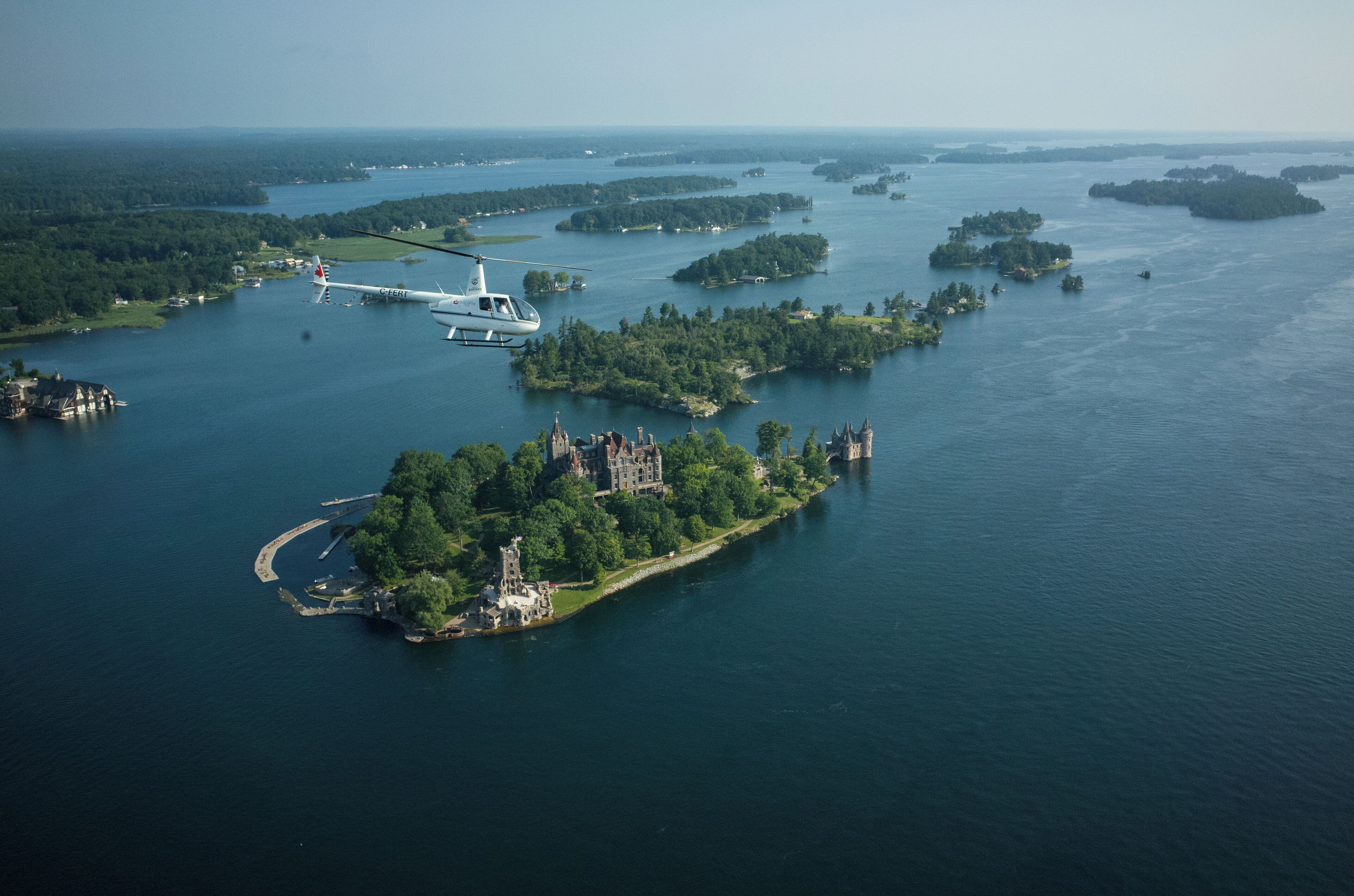 Vista aérea de una extensa masa de agua con varias islas, un helicóptero y una estructura parecida a un castillo en una de las islas.