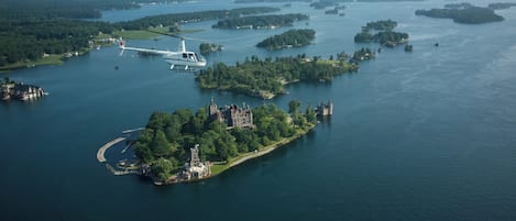 Vista aérea de una extensa masa de agua con varias islas, un helicóptero y una estructura parecida a un castillo en una de las islas.