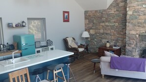A kitchen with a stone wall, a teal refrigerator, and a bar area.
