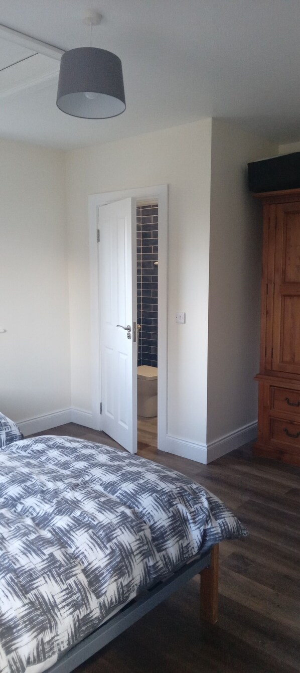 A bedroom with a bed, a wardrobe, and a door leading to a bathroom.