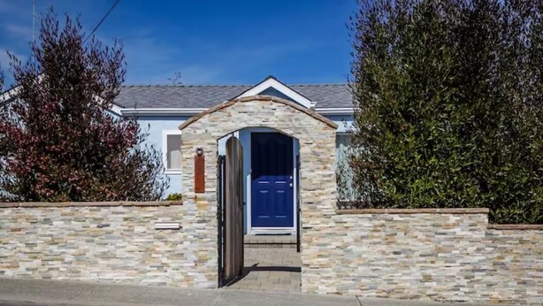 A house with a stone facade, a blue door, and a small porch. - Seaside Family House - Sleeps 6 on Monterey Peninsula (Seaside)