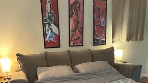 A bedroom with a large bed, a nightstand, a lamp, and three framed posters on the wall. - Seaside Family House - Sleeps 6 on Monterey Peninsula (Seaside)
