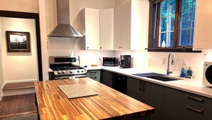 A modern kitchen with a central island, stainless steel appliances, and a window providing a view of the outdoors. - THE HIDDEN COTTAGE Private, Relaxing, Great Location, Has Everything You Need (Saugerties)