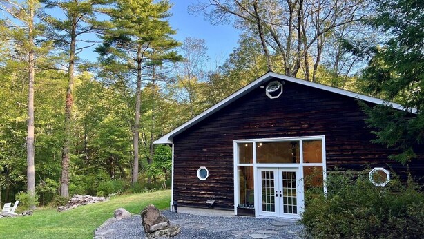A rustic cabin with a wooden exterior, a white door, and a stone pathway leading to the entrance. - THE HIDDEN COTTAGE Private, Relaxing, Great Location, Has Everything You Need (Saugerties)