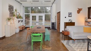 A spacious living area with a large window, a dining table with chairs, a sofa, and a small side table. - THE HIDDEN COTTAGE Private, Relaxing, Great Location, Has Everything You Need (Saugerties)