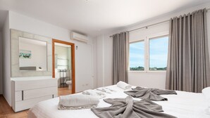 Hotellihuone, jossa on suuri sänky, yöpöytä, peili ja näkymä ulos.