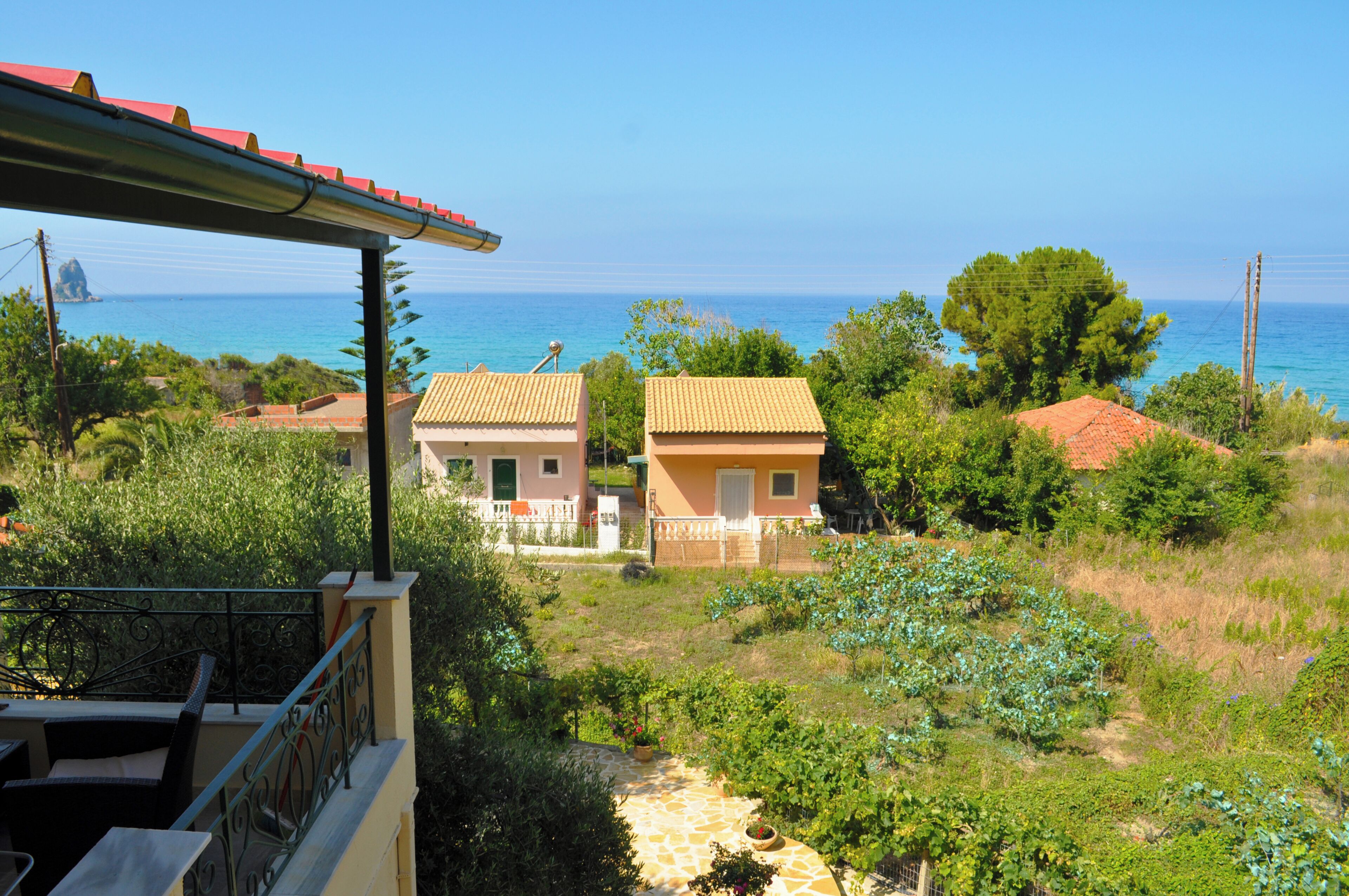 Une propriété située sur la côte, comprenant deux bâtiments, un balcon avec mobilier d’extérieur et une vue dégagée sur la mer.