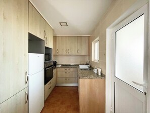 Eine kompakte Küche mit Kühlschrank, Herd, Mikrowelle und Spüle.
