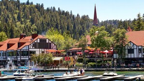 A riverside town with traditional buildings, a church spire, and boats docked at the pier. - Romantic A-Frame Cabin w/ Hot Tub, Fire Pit, Boulders, Fireplace, Hiking, Skiing (Running Springs)