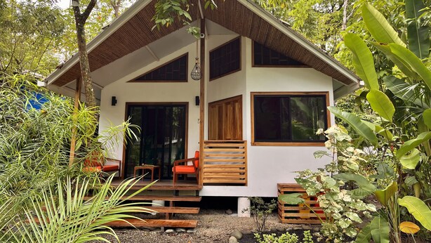 Une maison à deux étages avec un toit en pente, de grandes fenêtres et une terrasse en bois.