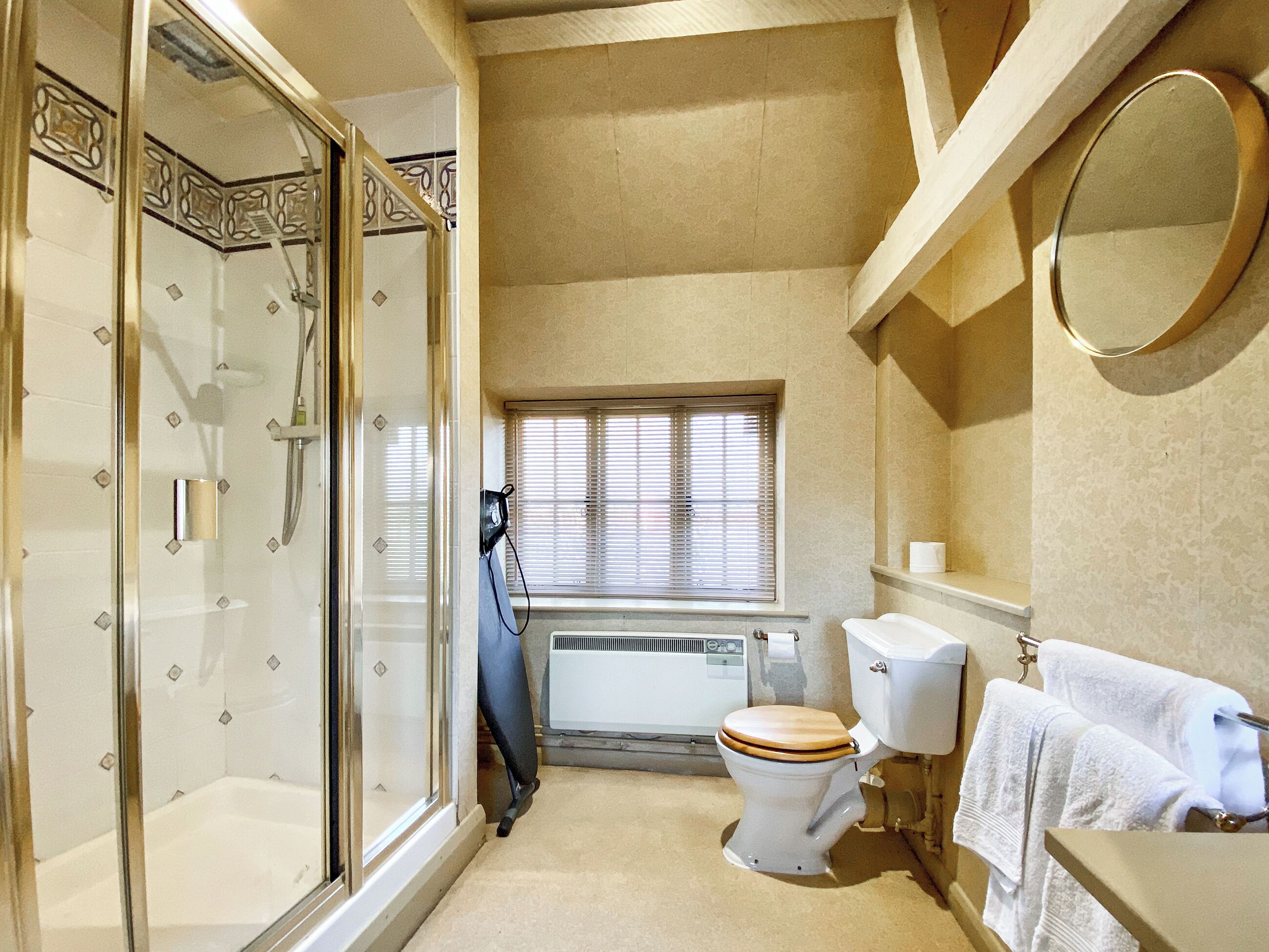 A bathroom with a glass shower enclosure, a toilet, a window, and a towel rack.